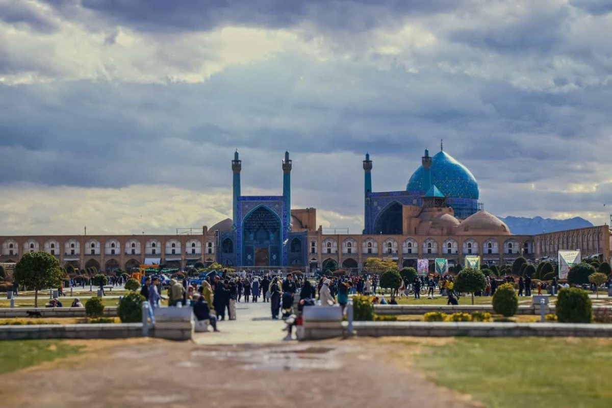 مسجد امام و گردشگران در میدان نقش جهان اصفهان زیر آسمان ابری